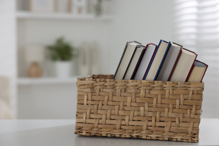 Different books in box on white desk indoors. Space for textの写真素材