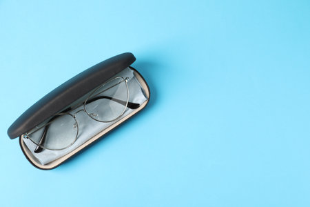 Case with stylish glasses and cleaning cloth on light blue background, top view. Space for textの写真素材
