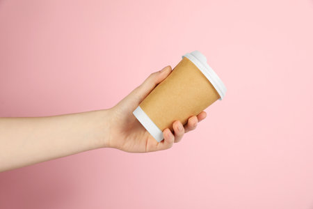 Woman holding paper cup on pink background, closeup. Mockup for designの写真素材