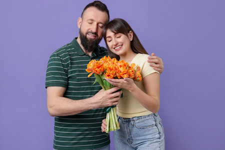 Lovely couple with bouquet of beautiful tulips on purple backgroundの写真素材