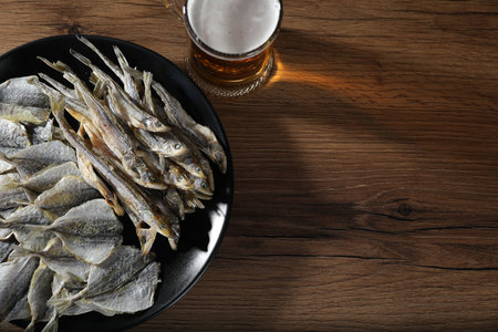 Dried fish and glass of beer on wooden table, flat lay. Space for textの写真素材