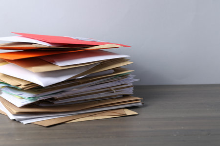 Post office. Stack of different paper envelopes on wooden table, closeup. Space for textの写真素材