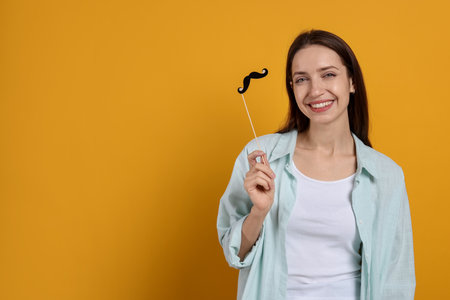 Happy woman with paper mustache on orange background. Space for textの写真素材