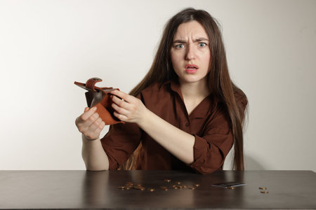 Upset woman with empty wallet at grey table. Financial problems