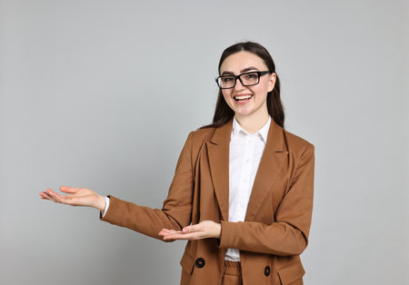 Happy businesswoman welcoming clients or partners on grey backgroundの写真素材