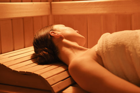 Beautiful woman relaxing on bench in saunaの写真素材