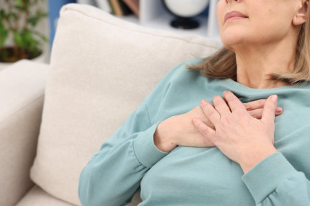 Heart attack. Senior woman suffering from pain in chest indoors, closeupの写真素材