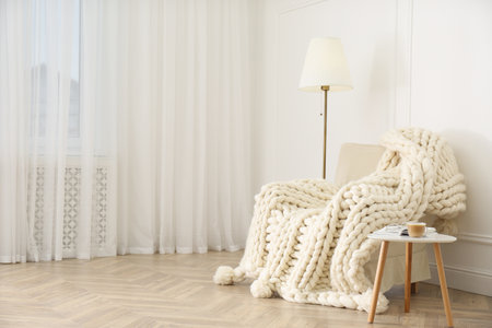 Knitted merino wool plaid on armchair in room.の写真素材