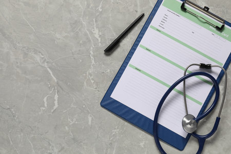 Medical card form, pen and stethoscope on grey background, top view. Space for textの写真素材