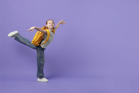 Stylish schoolgirl with backpack on violet background. Space for textの写真素材