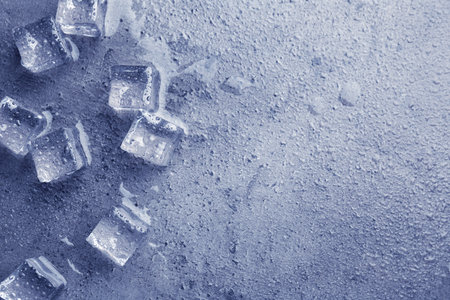 Melting ice cubes and water drops on blue textured table, flat lay.の写真素材