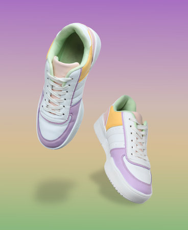 Stylish sneakers in air on color gradient backgroundの写真素材