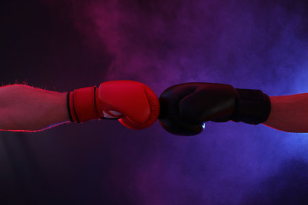 Men in boxing gloves fighting on dark background with smoke, closeupの写真素材