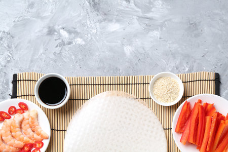 Rice paper sheets and different ingredients on light gray table, flat lay. Space for textの写真素材