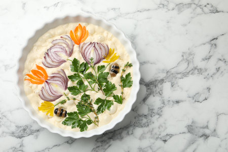 Raw focaccia with vegetables and olives in baking dish on white marble table, top view. Space for textの写真素材