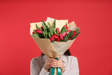 Woman with tulip flowers bouquet on red background. 8th of March celebrationの写真素材