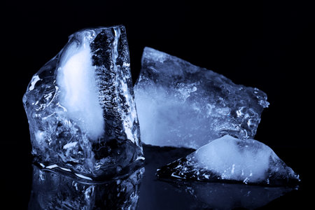 Pieces of clear ice on black mirror surfaceの写真素材