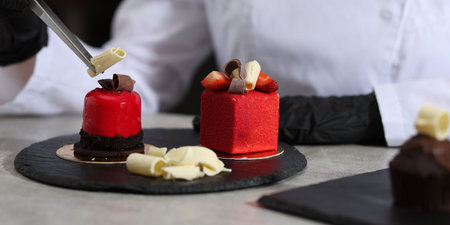 Confectioner decorating tasty dessert at light grey table in kitchen, closeupの写真素材