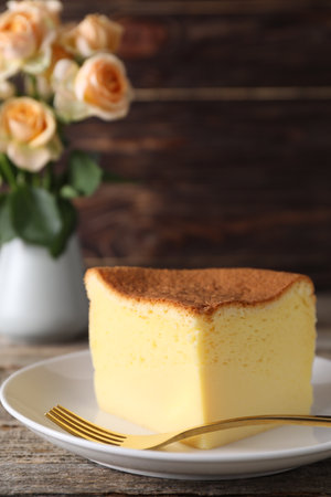Piece of tasty Japanese Castella sponge cake and fork on wooden table, closeupの写真素材