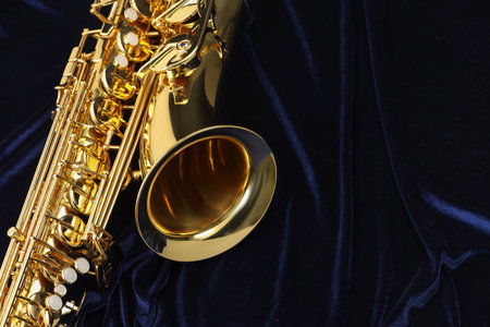 One beautiful saxophone on dark blue fabric, top view. Space for textの写真素材