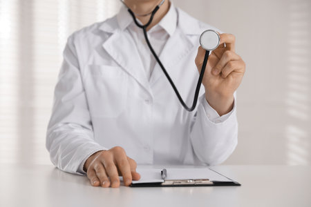 Doctor with stethoscope working at table in hospital, closeupの写真素材
