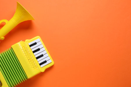 Toy accordion and horn on orange background, flat lay. Space for textの写真素材
