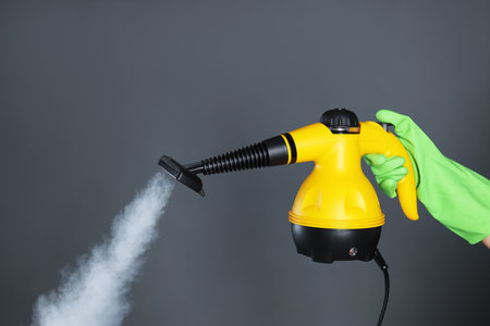 Woman with steam cleaner on grey background, closeupの写真素材