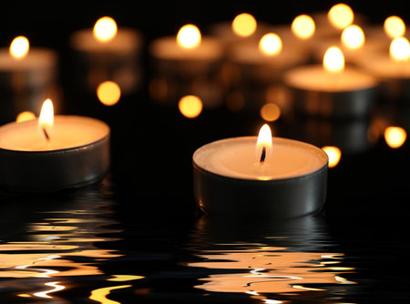 Candles burning on surface covered with water in darknessの写真素材