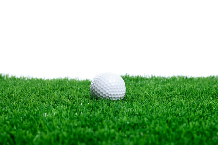 Golf ball on green grass against white backgroundの写真素材