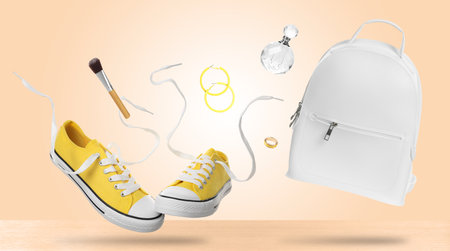 Shoes and accessories falling onto table against beige backgroundの写真素材