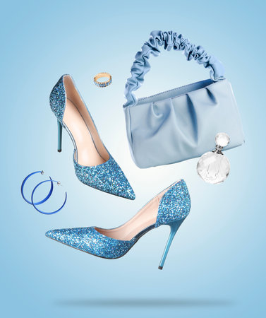 Fashionable shoes and accessories in air on light blue backgroundの写真素材