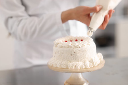 Confectioner decorating cake with cream at table, closeupの写真素材