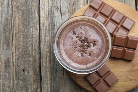 Tasty chocolate milk with shavings and pieces on wooden table, top view. Space for textの写真素材