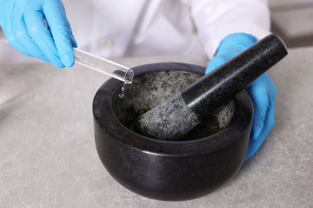 Biochemistry. Scientist with mortar and pestle working at gray table, closeupの写真素材