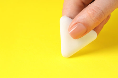 Woman using eraser on yellow background, closeup. Space for textの写真素材