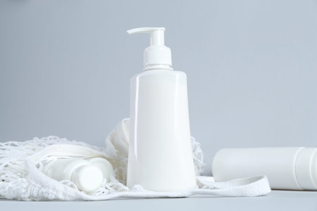 Many cosmetic products and mesh bag on light grey background