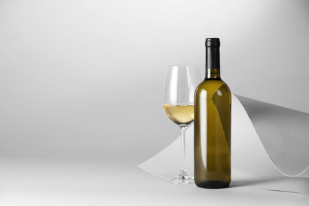 Bottle and glass of tasty wine on light grey background. Space for textの写真素材