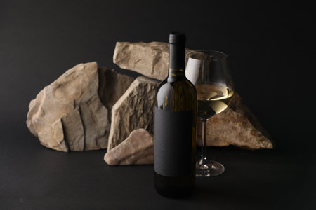 Bottle of wine, wineglass and rocks on black backgroundの写真素材