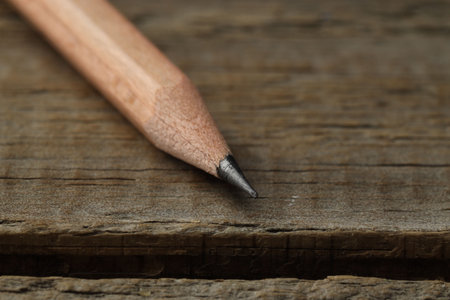 One sharp graphite pencil on wooden table, closeup. Space for textの写真素材