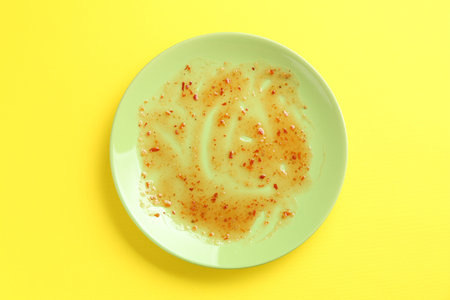 One dirty plate on yellow background, top viewの写真素材