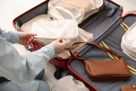 Woman zipping packing cube in suitcase indoors, closeupの写真素材