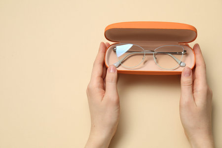 Woman with glasses in case on beige background, top view. Space for textの写真素材