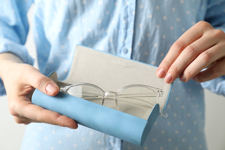 Woman holding case with stylish glasses on light background, closeupの写真素材