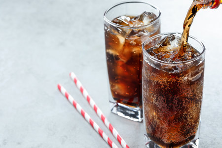 Pouring refreshing cola into glass on light table, closeup. Space for textの写真素材