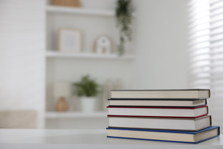 Stack of books on white desk indoors. Space for textの写真素材