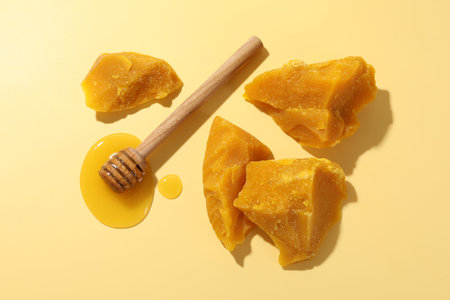 Candle making. Beeswax pieces and dipper with honey on beige background, flat lay