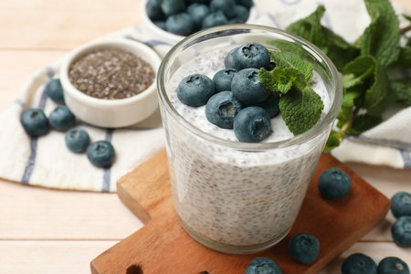 Delicious chia pudding with blueberries and mint in glass on wooden table, closeupの写真素材