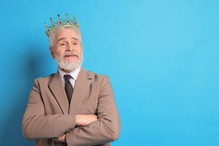 Senior man wearing luxury crown on light blue background, space for textの写真素材