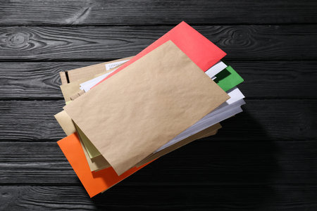 Different paper envelopes and parcel on black wooden table. Post office