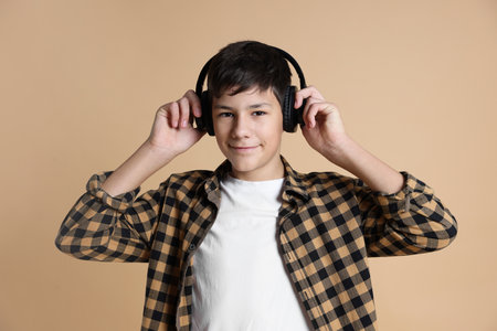 Portrait of teenage boy in headphones on beige backgroundの写真素材